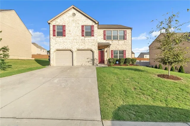 a view of a white house next to a yard with big trees