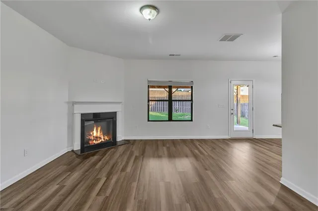an empty room with wooden floor fireplace and windows