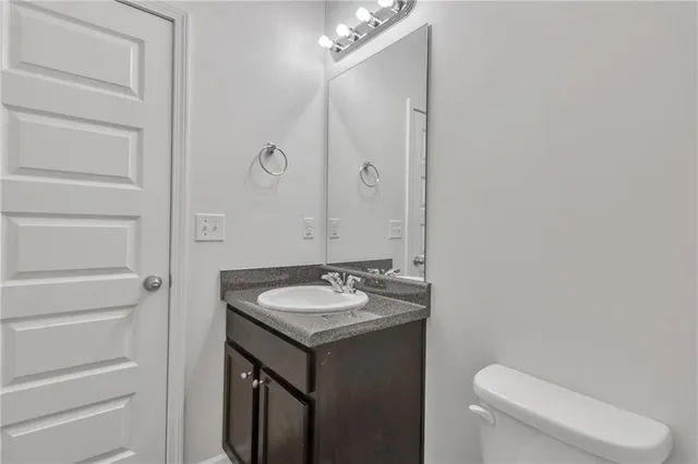 a bathroom with a granite countertop sink toilet and mirror