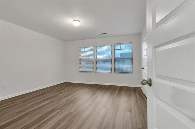 a view of an empty room with wooden floor and closet