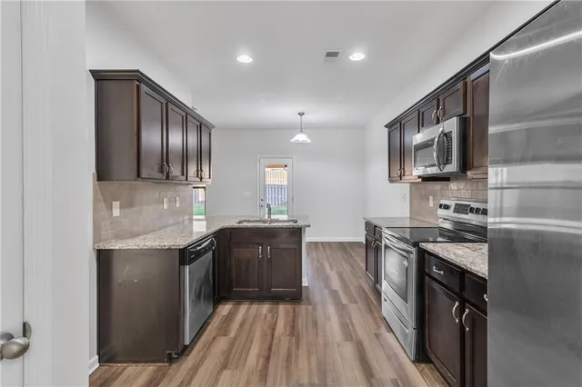 a kitchen with stainless steel appliances granite countertop a stove a sink and a refrigerator
