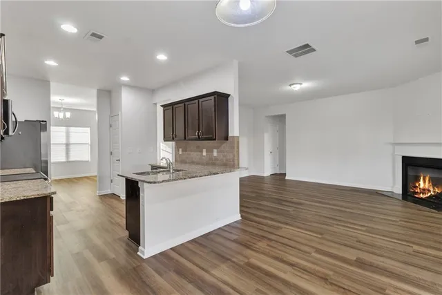 a large kitchen with stainless steel appliances granite countertop a stove and a wooden floors