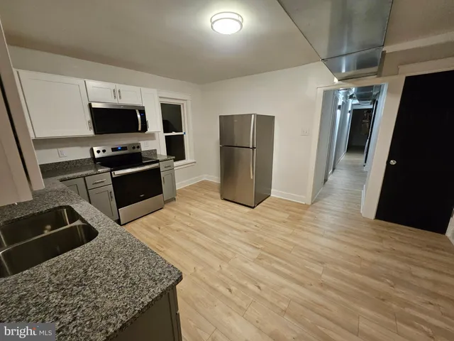 a kitchen with stainless steel appliances kitchen island granite countertop a refrigerator and a sink