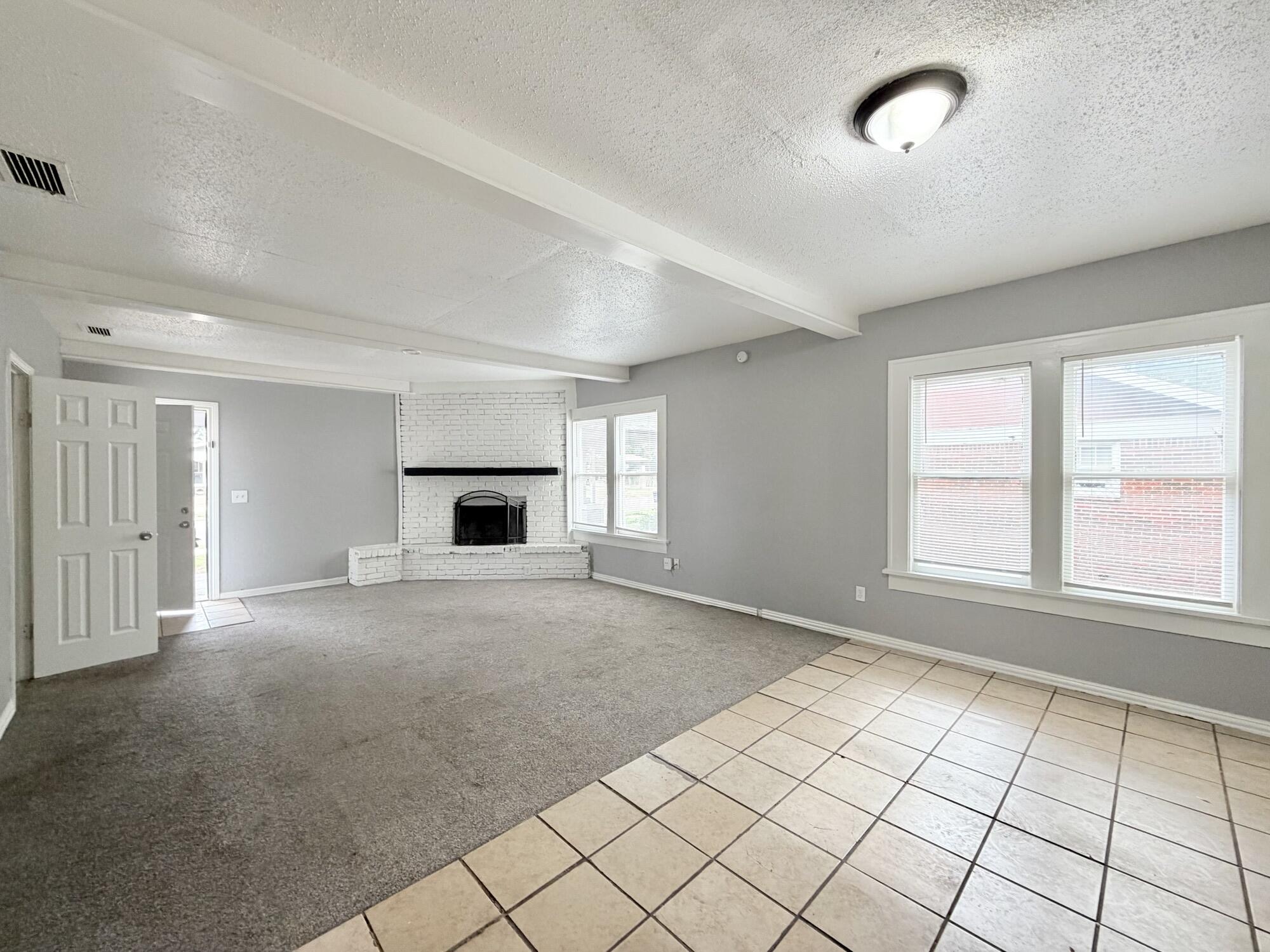 2119 15th Street Lubbock, TX 79401 - Photo 6 of 15 an empty room with windows and fireplace