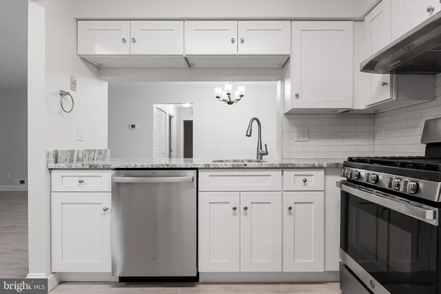 a kitchen with granite countertop white cabinets and stainless steel appliances