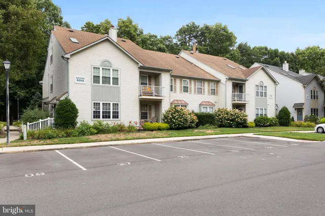 a view of a white house with a street next to a road