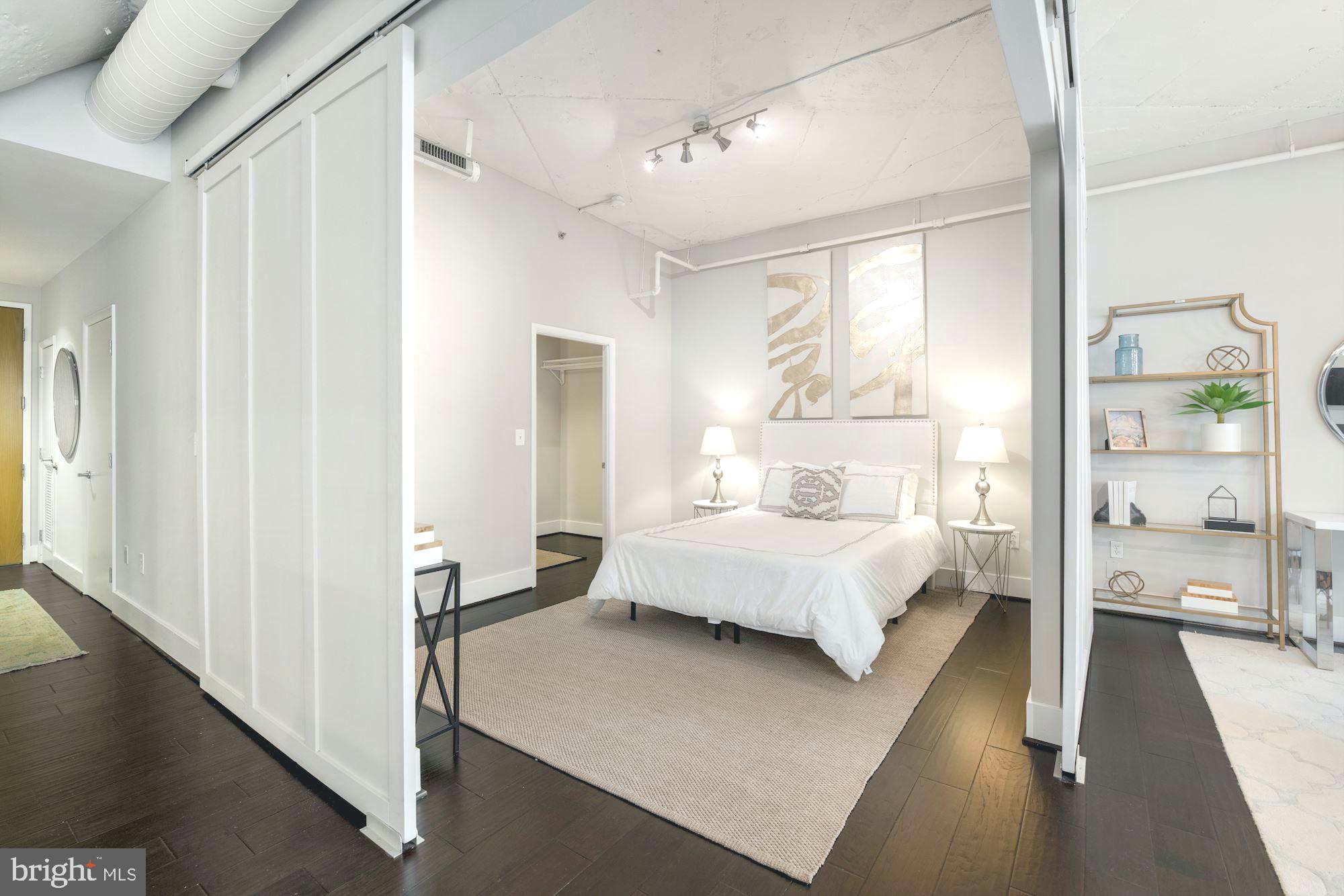 1700 Kalorama Road Northwest, Unit 207 Washington, DC 20009 - Photo 16 of 34 a spacious bedroom with a large bed and a walk in closet with wooden floor