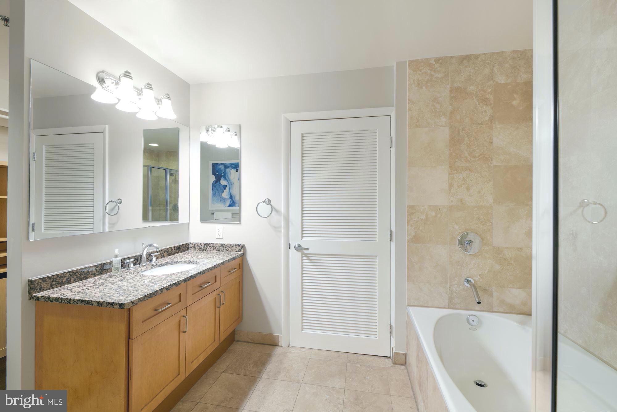 1700 Kalorama Road Northwest, Unit 207 Washington, DC 20009 - Photo 19 of 34 a bathroom with a granite countertop tub sink and mirror