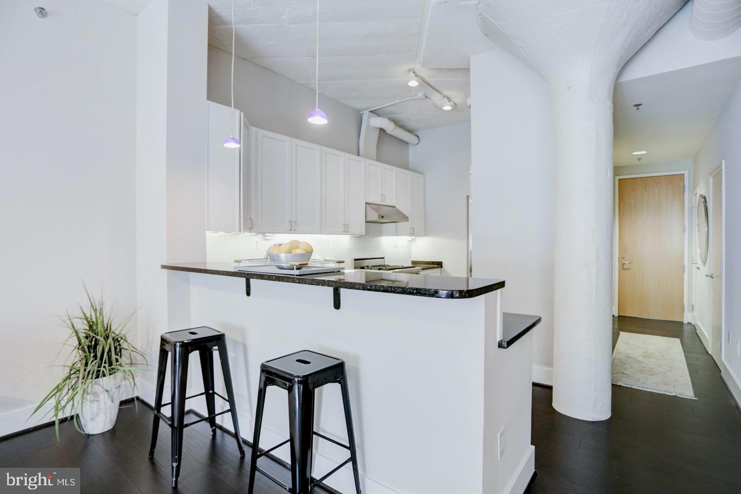 1700 Kalorama Road Northwest, Unit 207 Washington, DC 20009 - Photo 5 of 34 a kitchen with kitchen island stainless steel appliances a table chairs in it and wooden floor