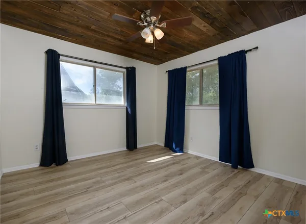 a view of empty room with wooden floor and fan