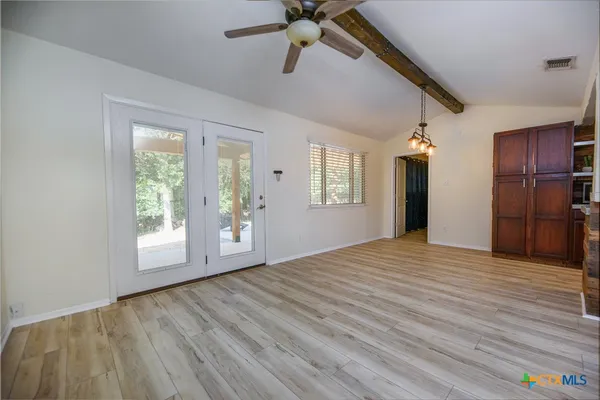 a view of an empty room with a window and wooden floor