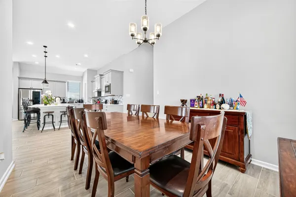 a dining area with furniture a chandelier and wooden floor