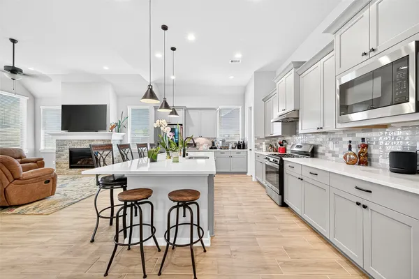 a kitchen with stainless steel appliances kitchen island granite countertop a stove top oven a sink dishwasher and a dining table with wooden floor