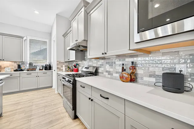 a kitchen with stainless steel appliances a sink dishwasher stove refrigerator and white cabinets with wooden floor