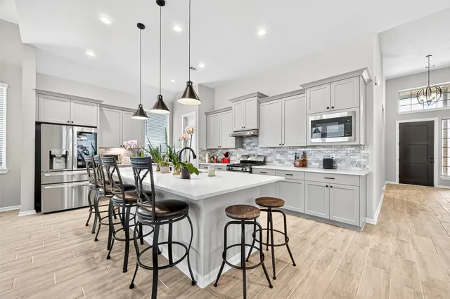a kitchen with stainless steel appliances kitchen island granite countertop a refrigerator a stove a kitchen island with a dining table and chairs