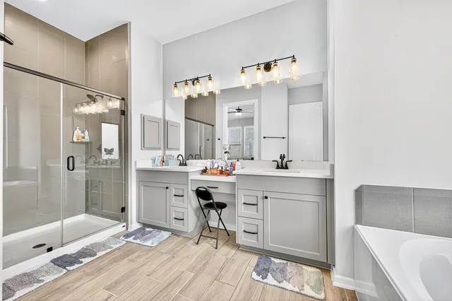 a bathroom with a double vanity sink mirror and a bathtub