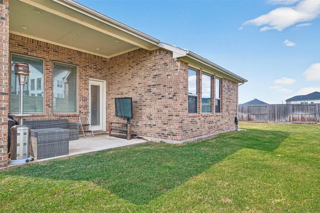 a brick house with a big yard and table and chairs
