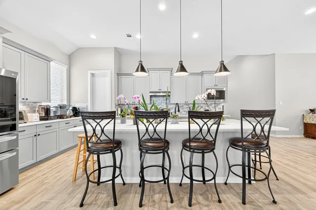 a dining hall with stainless steel appliances kitchen island granite countertop wooden floor dining table chairs and view of living room