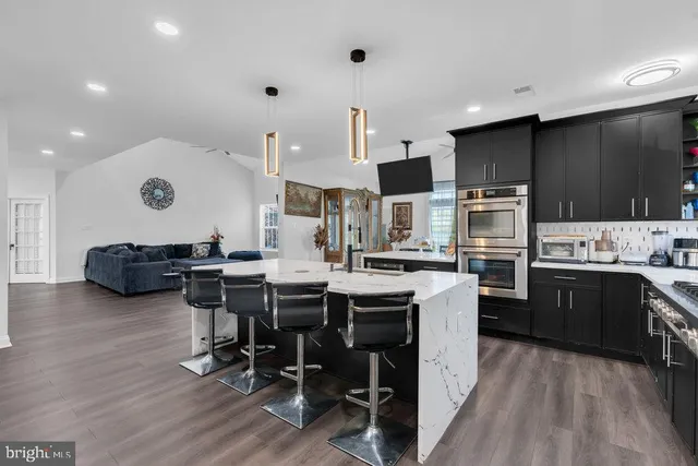 a kitchen with stainless steel appliances kitchen island granite countertop a table chairs sink and cabinets