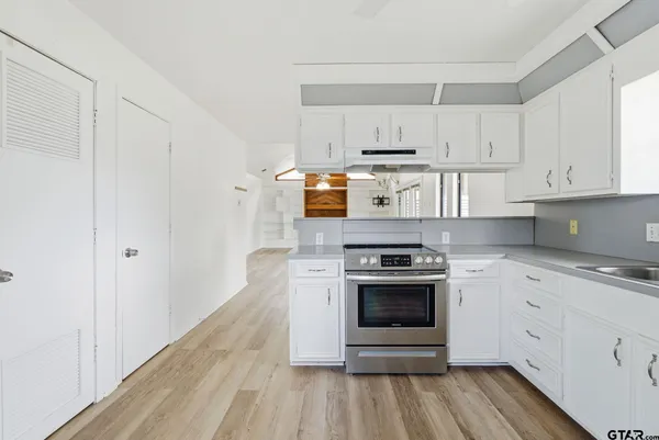 a kitchen with cabinets stainless steel appliances and wooden floor