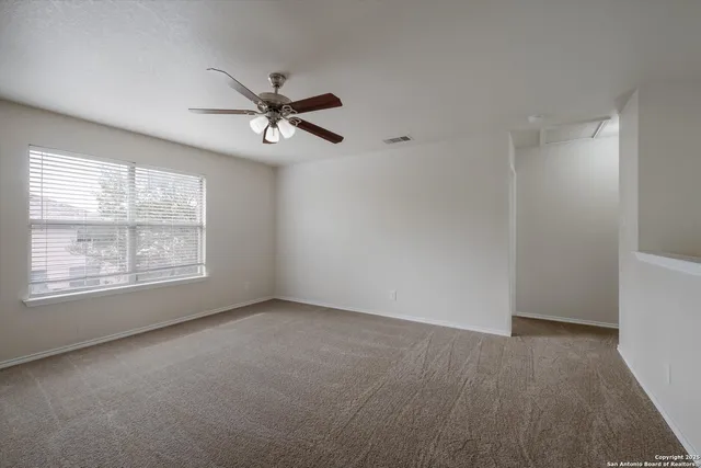 an empty room with windows and fan
