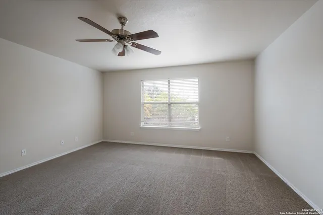 an empty room with a ceiling fan and windows