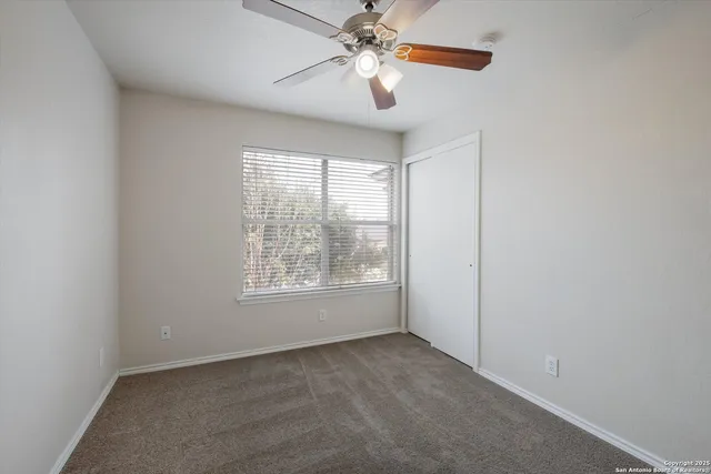 an empty room with windows and fan