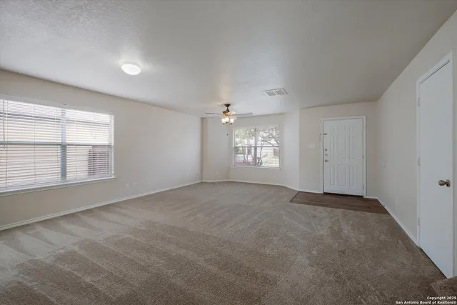an empty room with windows and ceiling fan