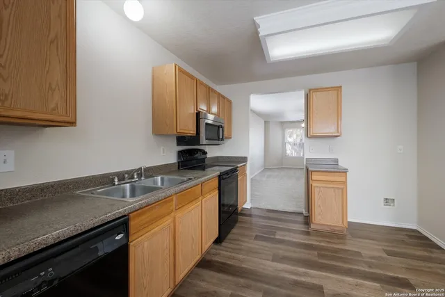 a kitchen with granite countertop a sink cabinets stainless steel appliances and a counter space