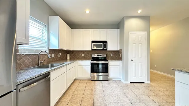 a large kitchen with granite countertop a stove a sink and a microwave