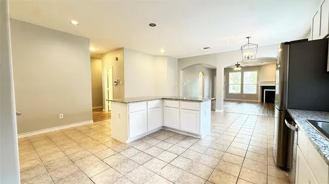 a view of a refrigerator in kitchen and an empty room