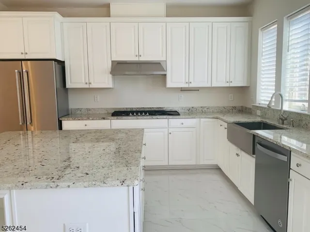 a white kitchen with granite countertop stainless steel appliances