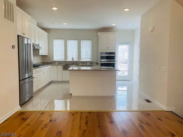 a large kitchen with stainless steel appliances granite countertop a stove a sink and a refrigerator