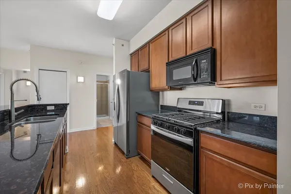 a kitchen with stainless steel appliances granite countertop a stove a sink and a microwave