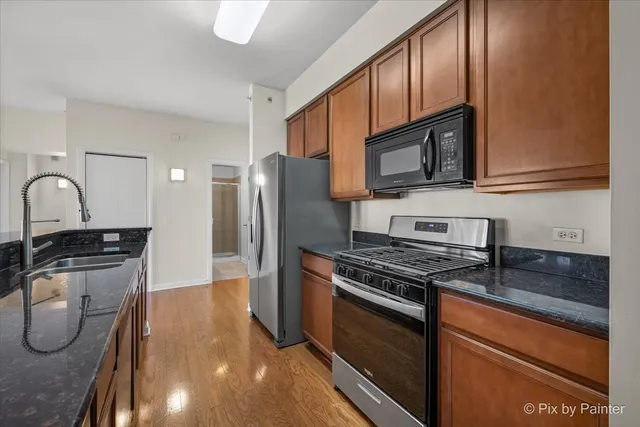 a kitchen with stainless steel appliances granite countertop a stove a sink and a microwave