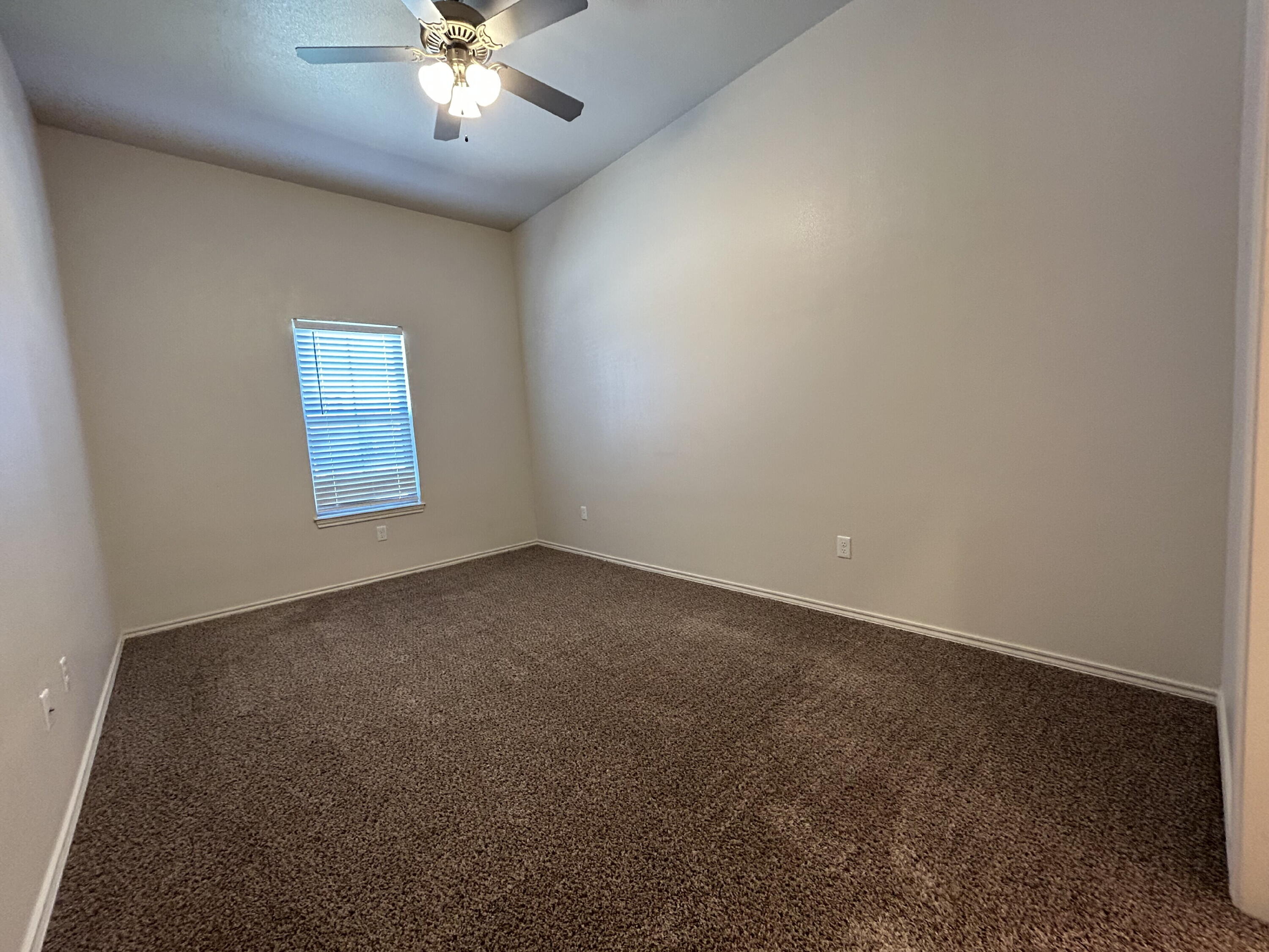 11620 Evanston Avenue Lubbock, TX 79424 - Photo 5 of 11 an empty room with a chandelier fan and windows