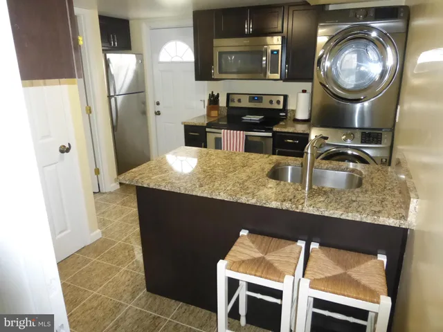 a kitchen with granite countertop a sink a stove and refrigerator