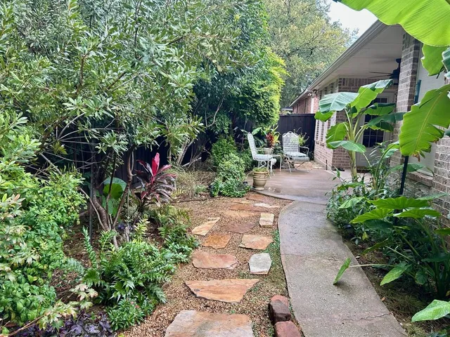 a backyard of a house with a garden and outdoor seating