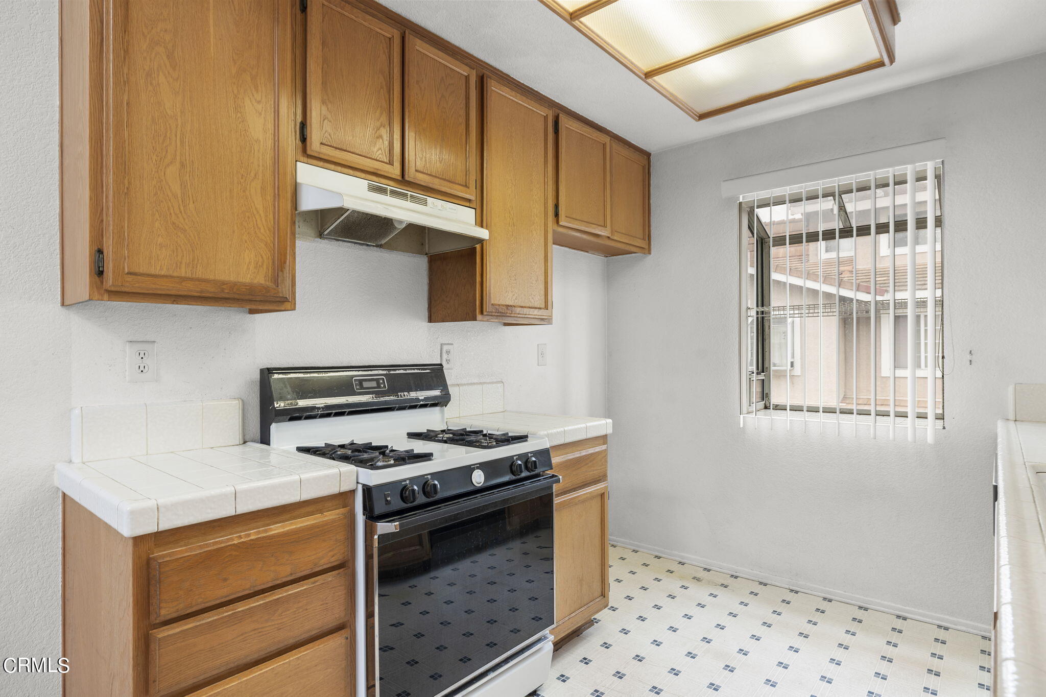 5182 Columbus Place Oxnard, CA 93033 - Photo 12 of 39 a kitchen with wooden cabinets and a stove top oven