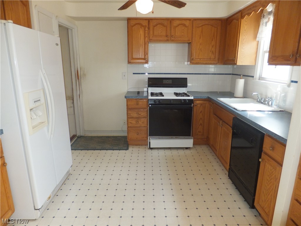 7701 Spring Garden Road Cleveland, OH 44129 - Photo 5 of 27 Kitchen featuring backsplash, brown cabinets, white appliances, ceiling fan, and light tile flooring