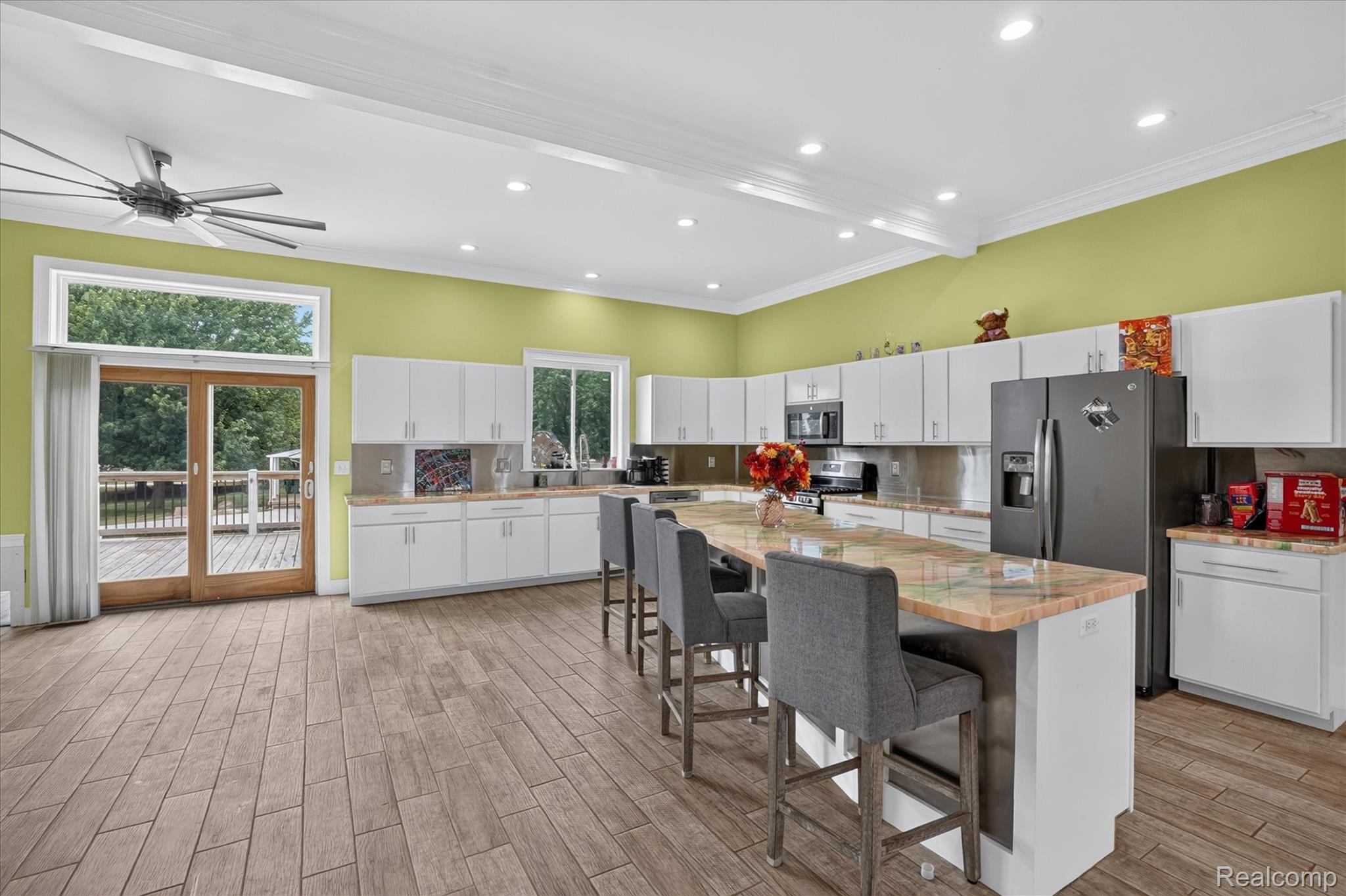 6524 Kelly Road Flushing, MI 48433 - Photo 11 of 47 Spacious kitchen featuring an expansive central island with seating, abundant white cabinetry, stainless steel appliances, and wood-finish flooring