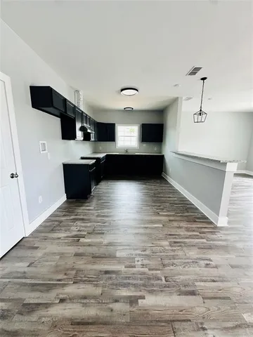 a view of kitchen with stainless steel appliances wooden floor and chair