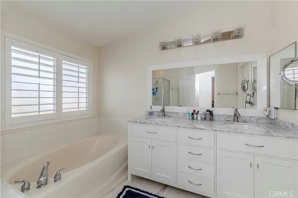 a bathroom with a granite countertop sink mirror bathtub and double