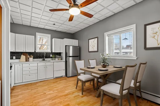 a kitchen with stainless steel appliances granite countertop a dining table chairs cabinets a sink and a window