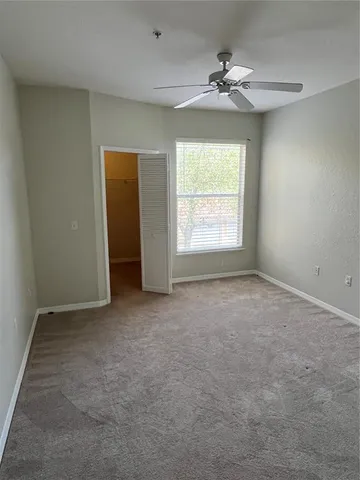 an empty room with a window and a ceiling fan