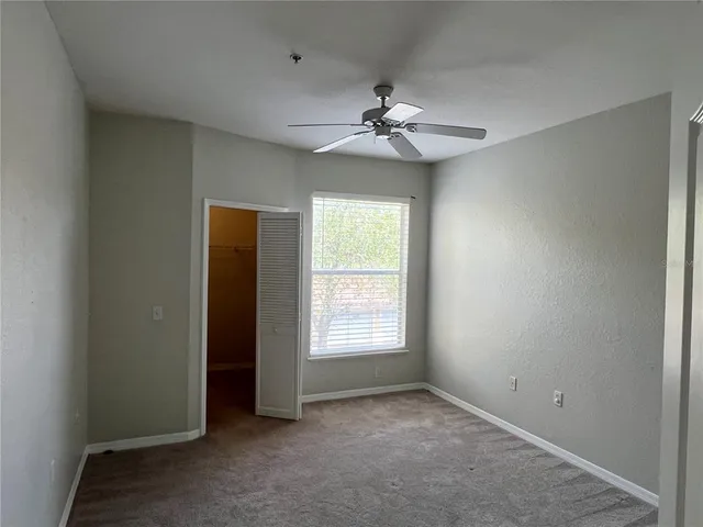 an empty room with windows and fan