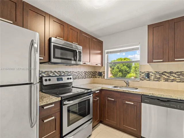a kitchen with granite countertop a sink stove and microwave