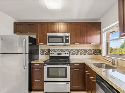a kitchen with granite countertop a refrigerator stove and sink