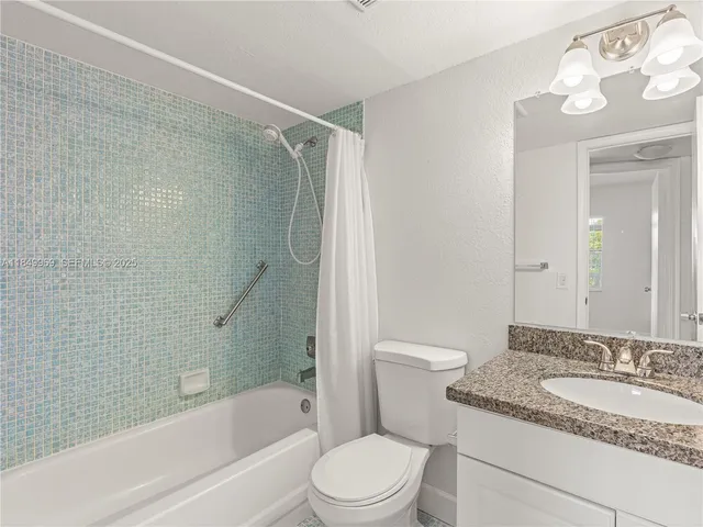 a bathroom with a granite countertop bathtub shower sink vanity and toilet