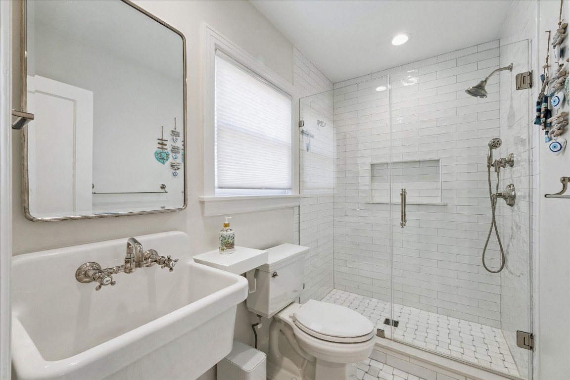 1925 Banks Street Houston, TX 77098 - Photo 16 of 38 Beautiful clean & bright full downstairs bathroom off of the laundry room features a sleek, modern design with a large, frameless glass shower, white subway tiles, and a classic pedestal sink. It offers a clean and bright aesthetic with ample natural light.